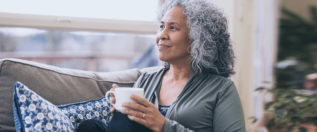 A woman sitting on the couch holding a cup.