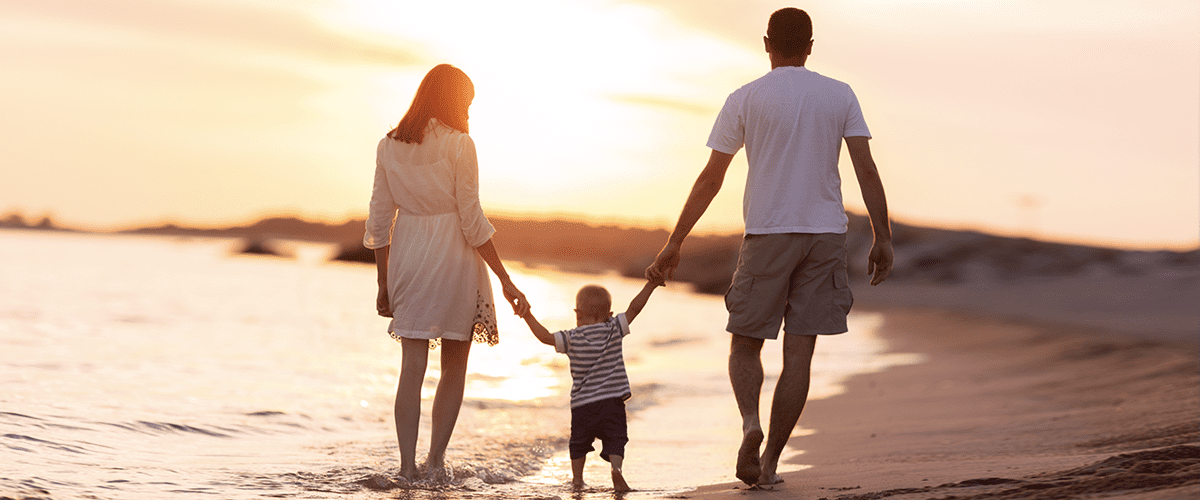 A man, woman and child walking on the beach